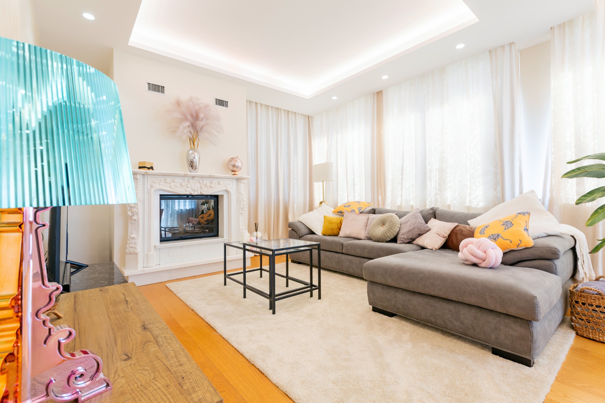 Living con divano angolare, camino in marmo e lampada turchese