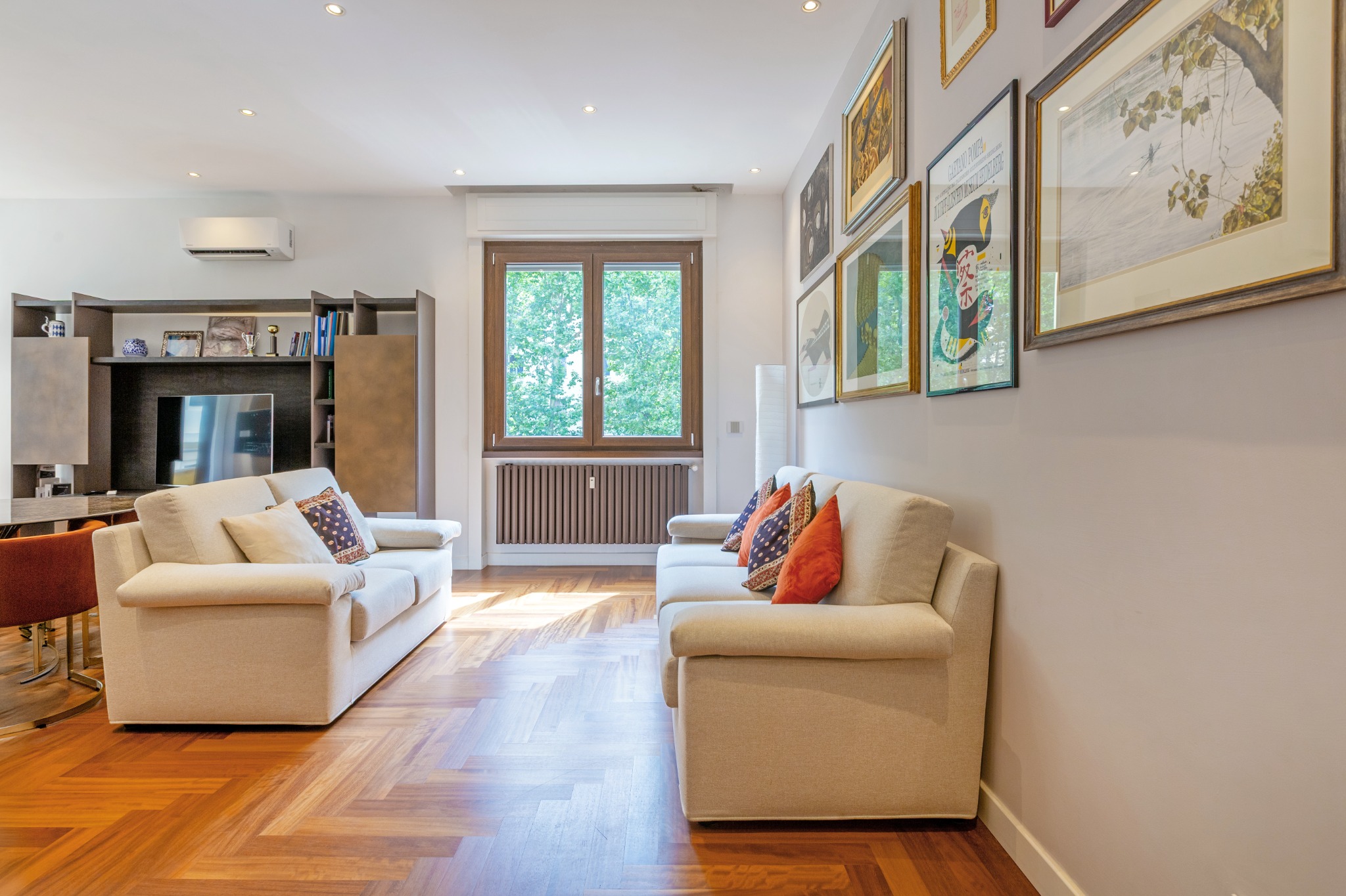 Zona relax con divani chiari e galleria di quadri