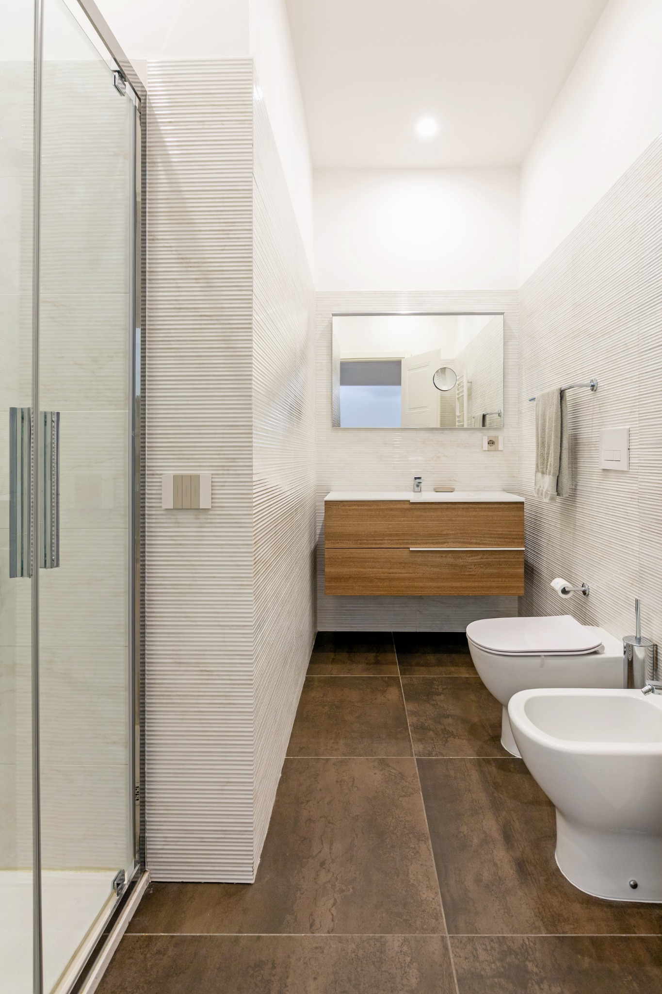 Bagno con mobile lavabo in legno e rivestimenti chiari a rilievo